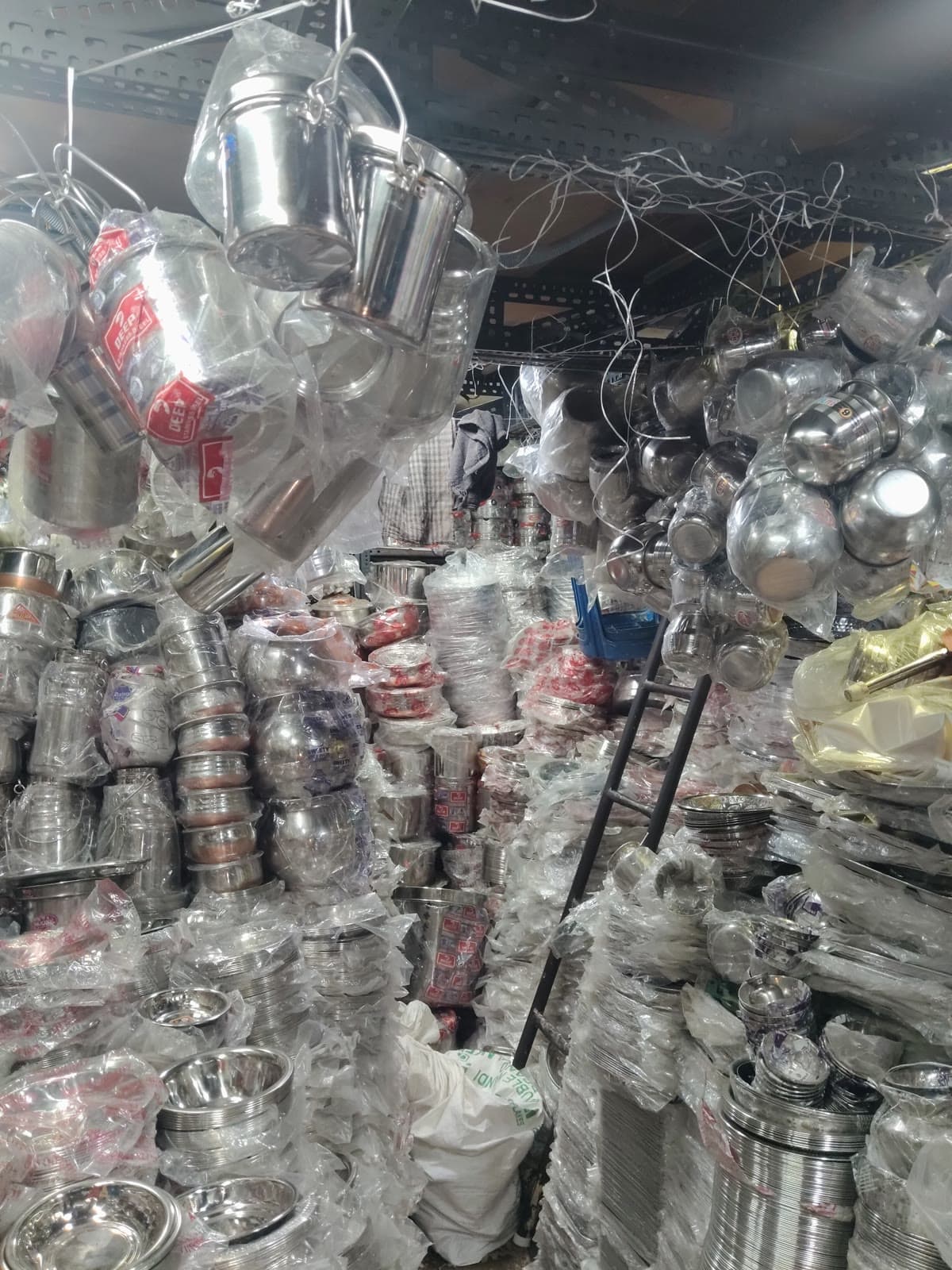 Kitchen tools aisle with steel cups, plates, spatulas, and hanging utensils